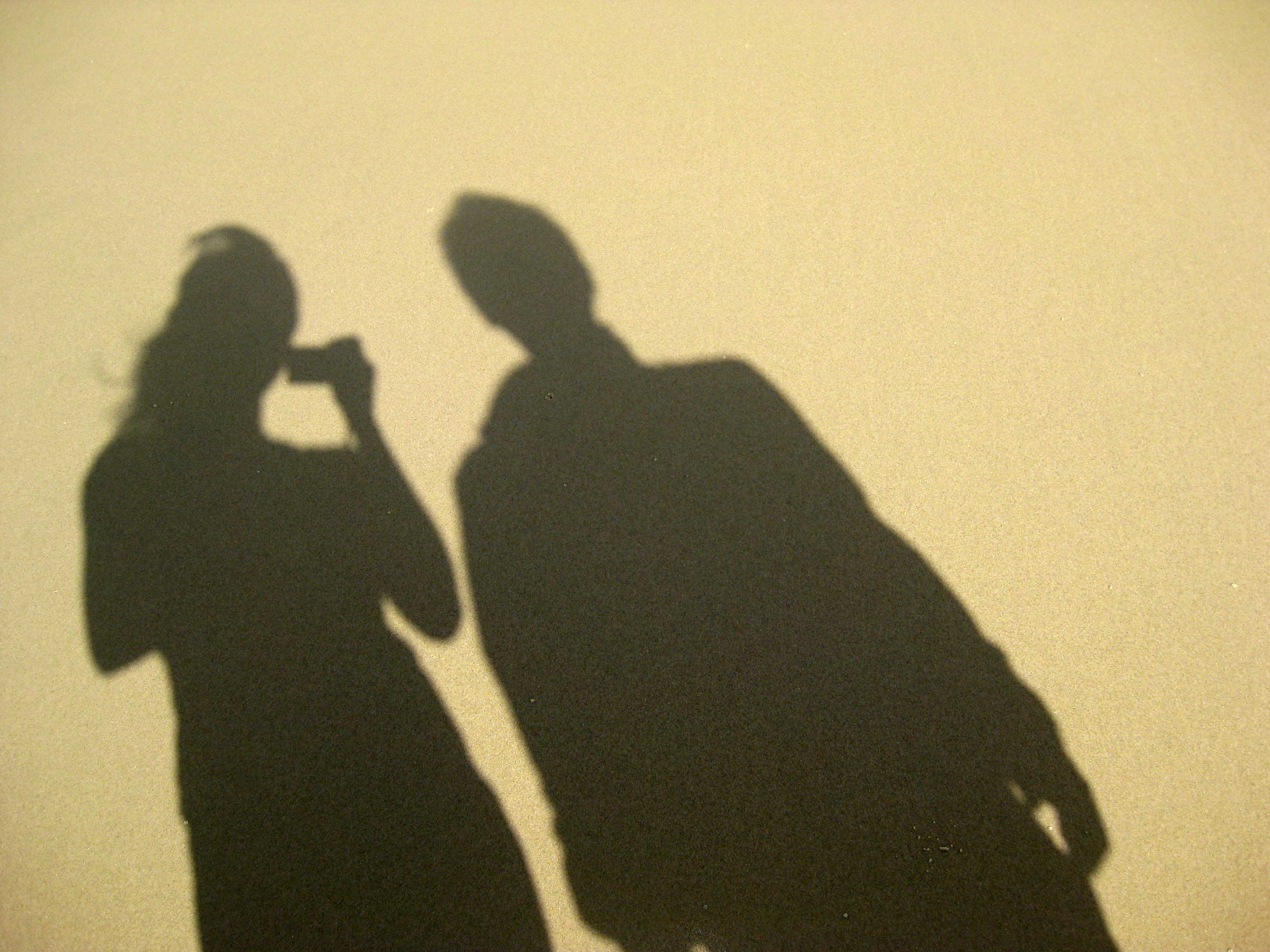 shadow image of you and your brother in sand while you travel with your brother